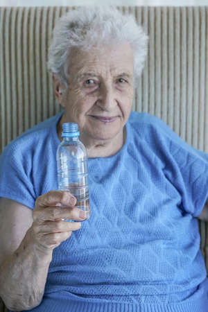 A lovely senior woman holding a bottle of drinking waterの写真素材
