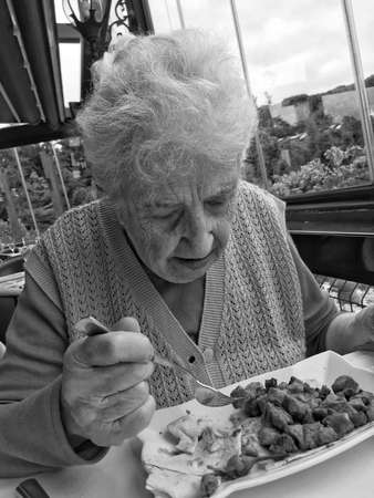 A lovely elderly woman having lunch in a restaurant.の写真素材