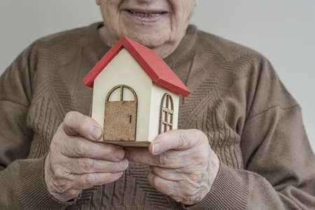 A Senior woman holding small wooden houseの写真素材