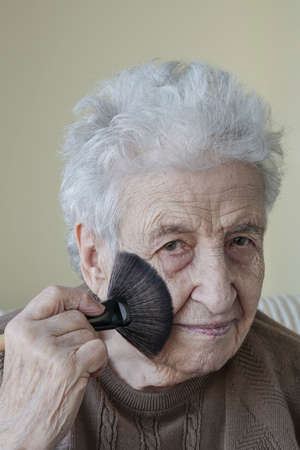 A lovely senior woman doing makeup with brushの写真素材