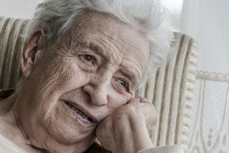 Closeup portrait of sad and thoughtful elderly woman at home