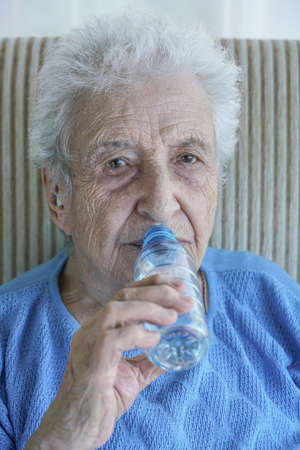 A lovely senior woman drinking water from a bottle