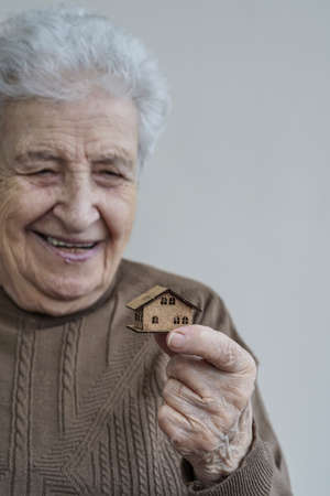 A senior woman holding a small wooden houseの写真素材