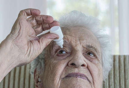 A senior woman applying  eye drop by herselfの写真素材