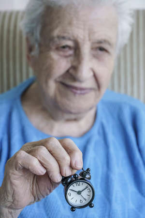 A happy senior woman holding a clock
