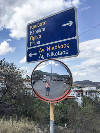 Road mirror and sign showing the direction in Crete Island, Greece.のeditorial素材