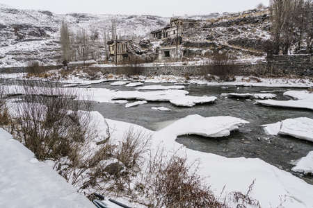 Old buildings by frosted river in Kars city in Turkey