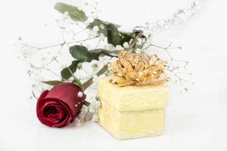 A red rose and yellow gift box on white