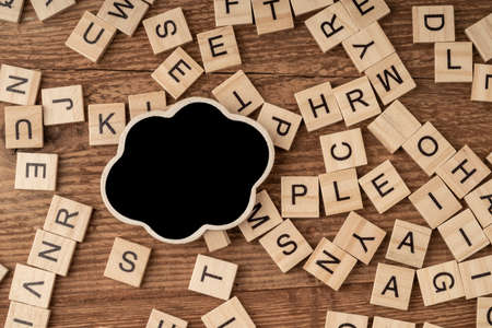 an empty chalkboard and cube alphabets on a wooden surfaceの写真素材