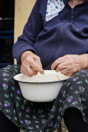 closeup hands of a senior woman preparing green beans for cookingの写真素材