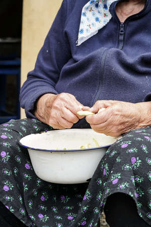 closeup hands of a senior woman preparing green beans for cookingの写真素材