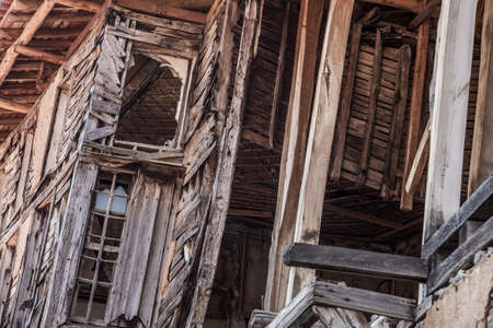 an abandoned wooden building with damaged wall and windowsの写真素材