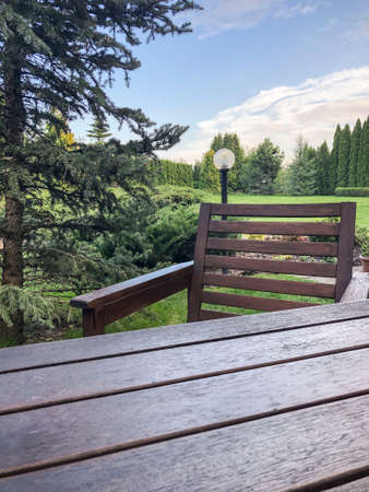 an empty wooden table and chair at a garden in summerの写真素材