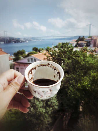 hand holding a cup of turkish coffee against sea view in Istanbul, Turkey