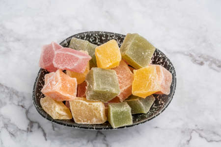 closeup colorful turkish delights in a bowl on a marble tableの写真素材