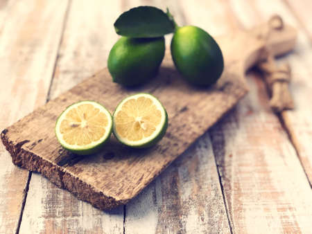 whole and sliced limes on a wooden cutting board on a tableの写真素材