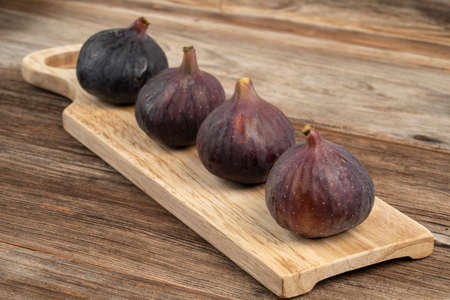 ripe purple figs on a wooden cutting board on a tableの写真素材