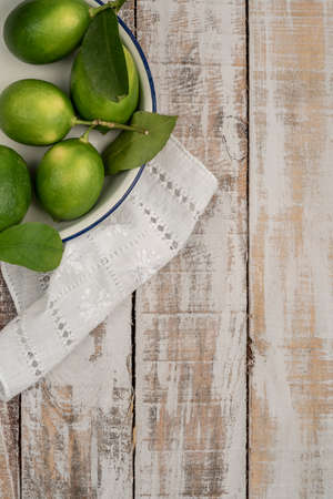 fresh green limes on a wooden table with copy spaceの写真素材