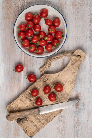 ripe cherry tomatoes and knife on a wooden table with copy spaceの写真素材