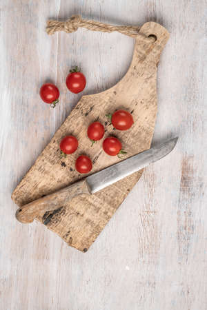 ripe cherry tomatoes and knife on a wooden table with copy spaceの写真素材