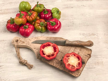 cut and whole bell peppers on a cutting board on a wooden table