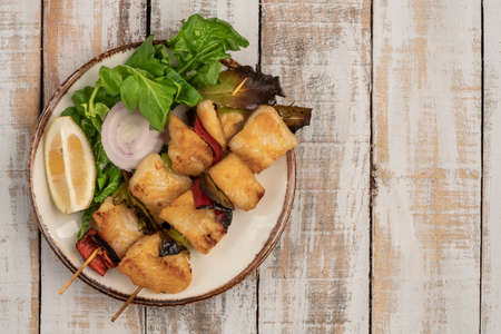 Skewed sole fish served with salad on a wooden tableの写真素材