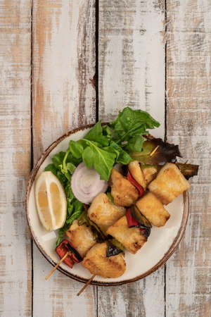 Skewed sole fish served with salad on a wooden tableの写真素材