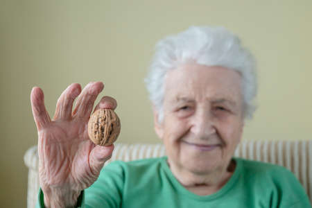 A happy senior woman holding walnut