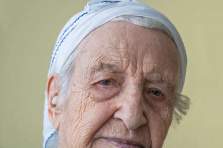 closeup wrinkled face of a thoughtful senior woman with hearing aid