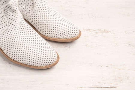 pair of brand new stylish white boots for summer on a wooden background