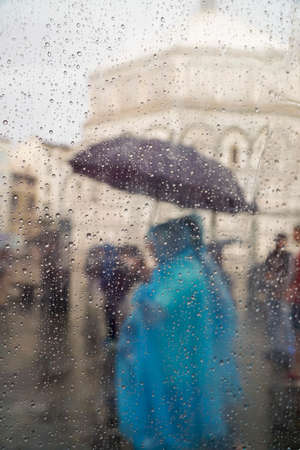 background with rain drops on window pane against people at streetの写真素材