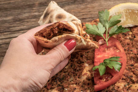 closeup female hand wrapping Lahmacun, Turkish pizza inorder to eat