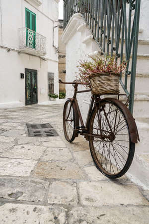 an old and rusty bike lean on wall at streetの写真素材