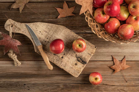 ripe red apples on a wooden cutting boad on table decorated with leaves