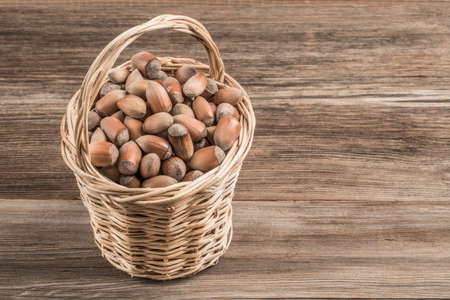 raw hazelnuts in a basket on wooden table with copy space