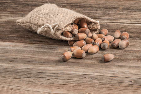 raw hazelnuts in a burlap sack on a wooden tableの写真素材