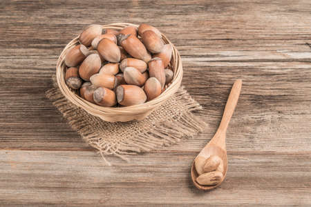 raw hazelnuts in a basket on a wooden tableの写真素材