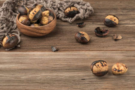 roasted chestnuts in a bowl on a wooden table with copy space