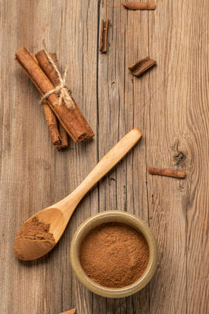 cinnamon powder and sticks on a wooden table with copy space, flat layの写真素材