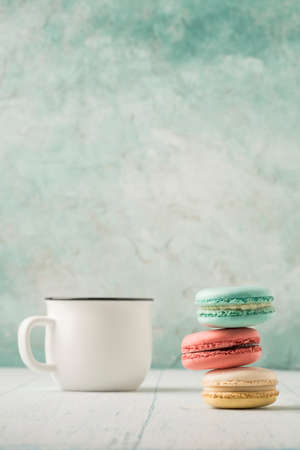 pile of colorful french macaroons and a cup of coffee on table over green with copy spaceの写真素材