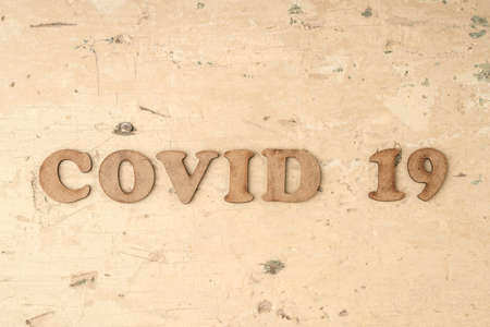 Epidemic corona virus covid 19 written with carved wooden letters on tableの写真素材