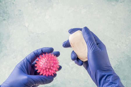 closeup hands in blue latex disposable surgical gloves holding virus and soap bar