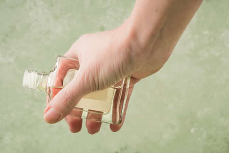 closeup hand of a person holding a bottle of cologne