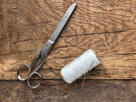scissors and spool of white thread, rope on a wooden tableの写真素材