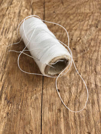 closeup spool of white thread on a wooden table