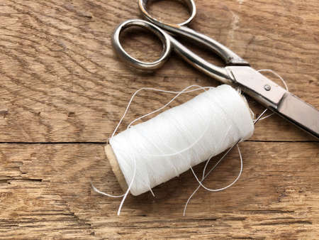 scissors and spool of white thread, rope on a wooden tableの写真素材