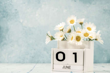 White cube calendar for june decorated with daisy flowers over blue background with copy spaceの写真素材