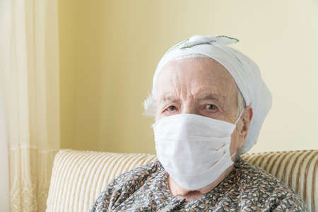 old woman wearing medical mask for protection of covid19 virus at homeの写真素材