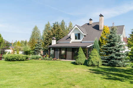 a beautiful village house with its beautiful garden in a rural area under blue skyの写真素材