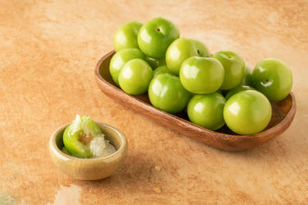 closeup fresh and ripe green plums on a table served with salt to dip themの写真素材